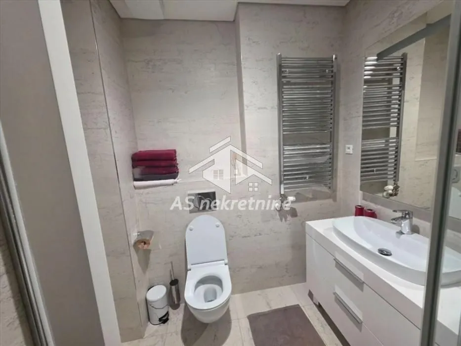 Modernly equipped bathroom with a washbasin, toilet, and towel warmer.