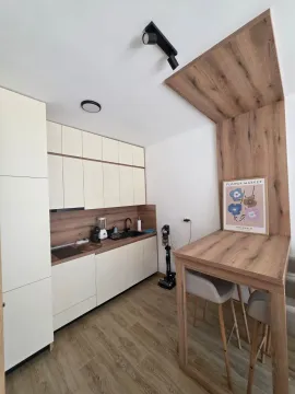 Moderna kuhinja sa bijelim elementima, drvenim radnim dijelom i trpezarijskim stolom. - image 6