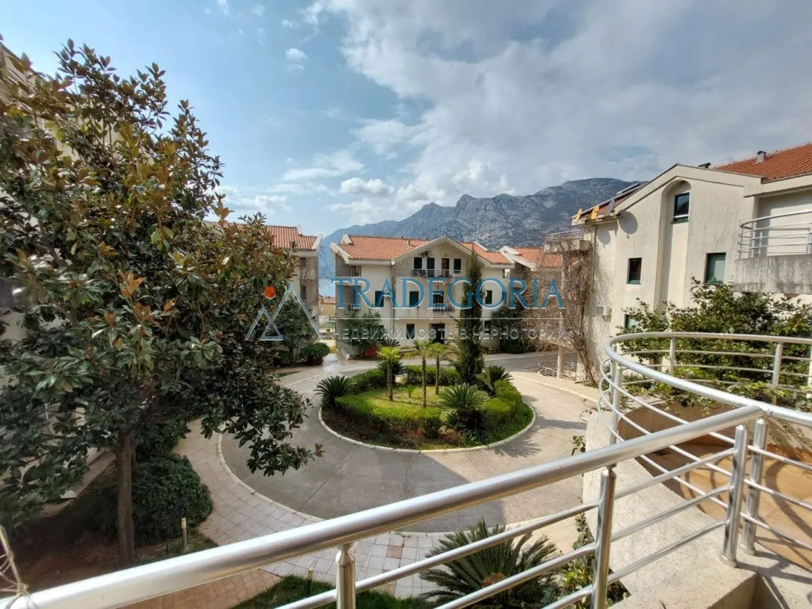 Pogled sa terase na uređeno dvorište i okolne zgrade sa planinama u pozadini.