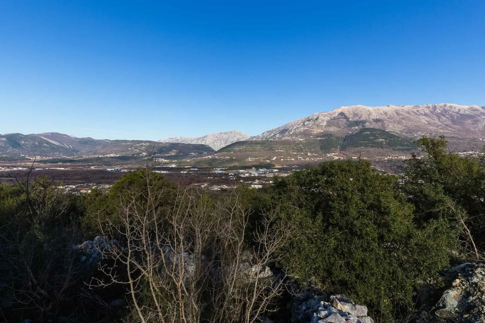Pogled na okolne planine i dolinu sa zelenilom u prvom planu.