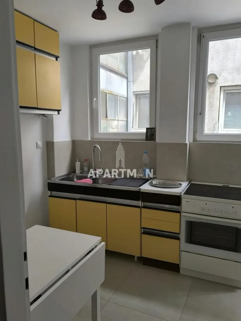 Small kitchen with yellow cabinets and a stove.