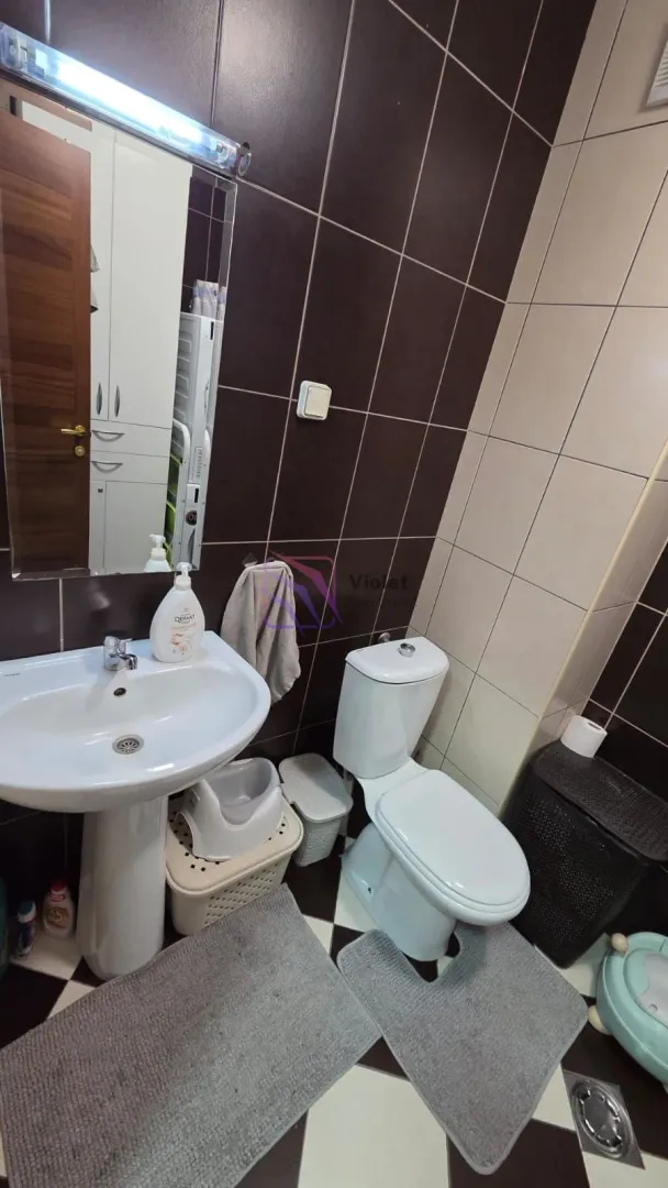 Kupatilo opremljeno umivaonikom, WC šoljom i ogledalom.