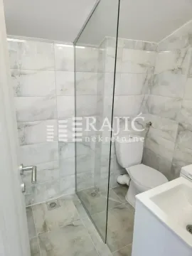 Small bathroom with a walk-in shower and white tiles. - image 8