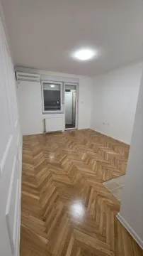 Prazna soba sa drvenim parketom, belim zidovima i klima uređajem. - image 4