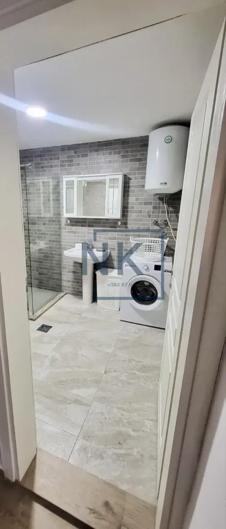 Bathroom equipped with a shower cabin, washbasin, and washing machine.