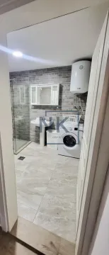 Bathroom equipped with a shower cabin, washbasin, and washing machine. - image 5
