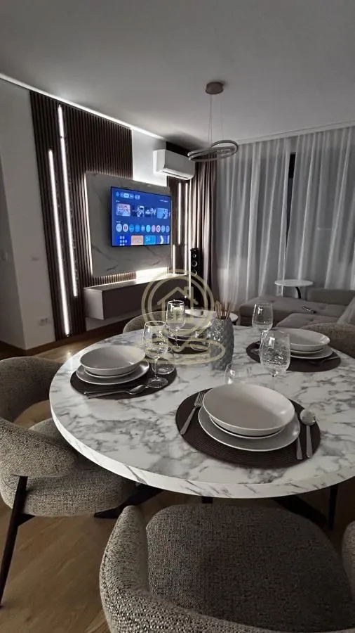 Living room with a round dining table and a TV on the wall.