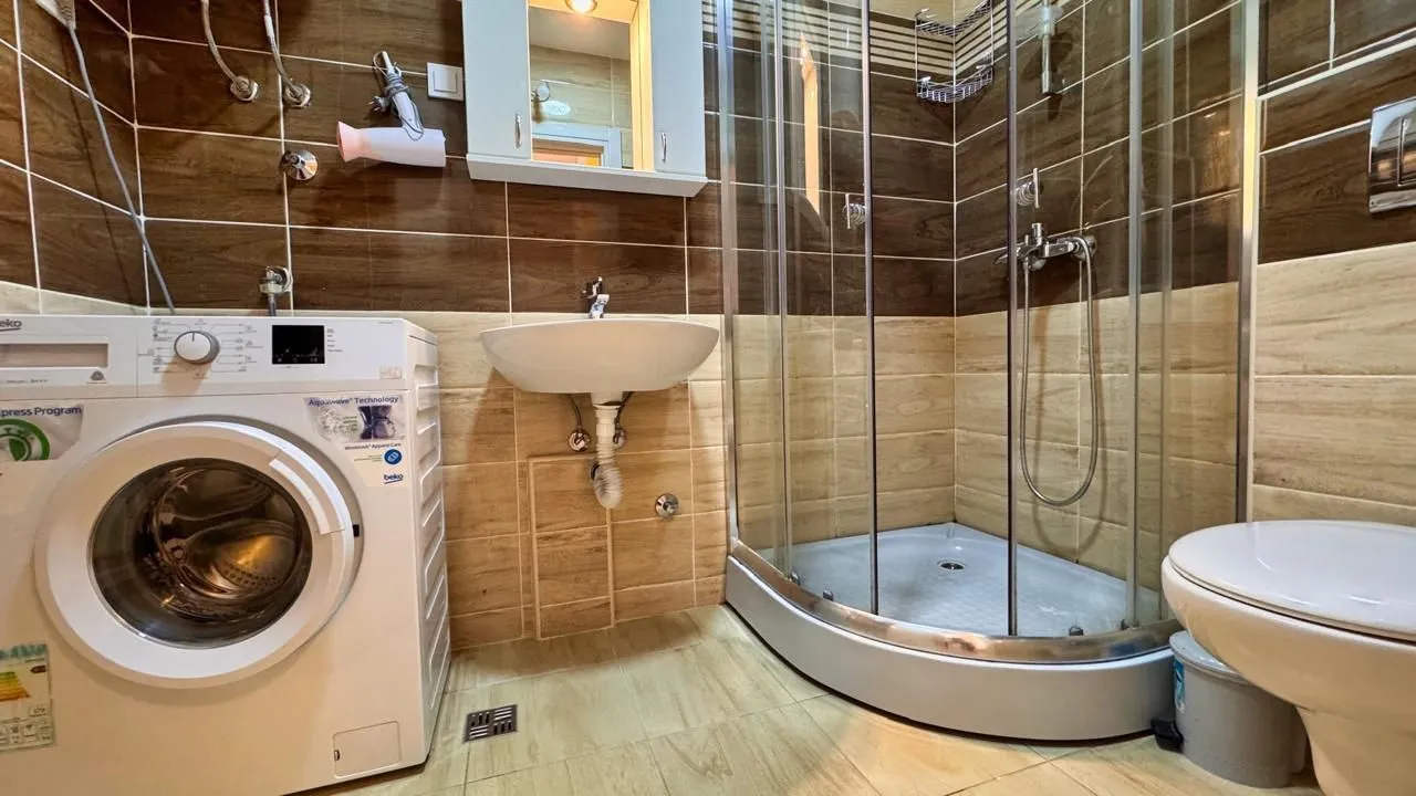 Bathroom equipped with a shower cabin, washbasin, toilet, and washing machine.