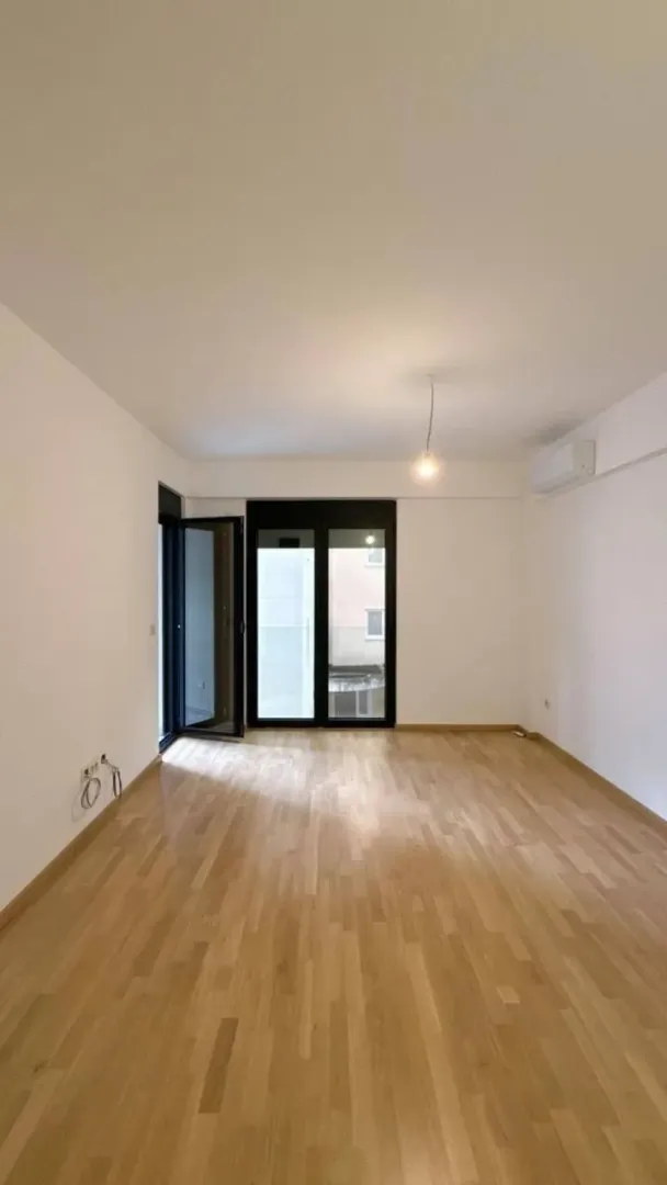 Empty room with hardwood floors and balcony doors.