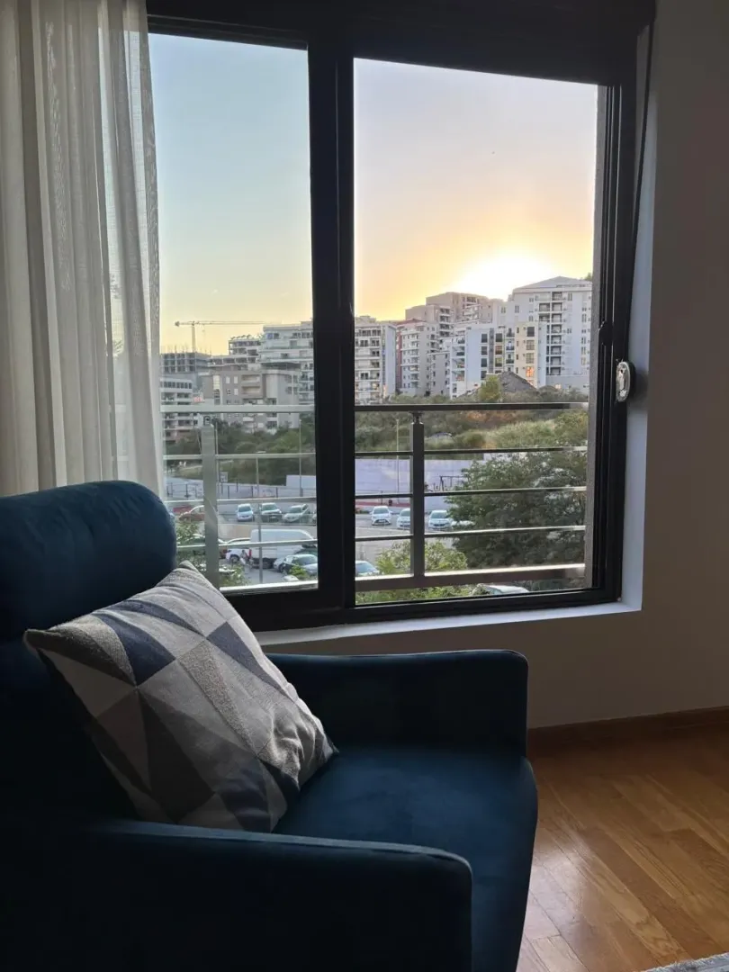 A comfortable blue armchair by the window with a city view.