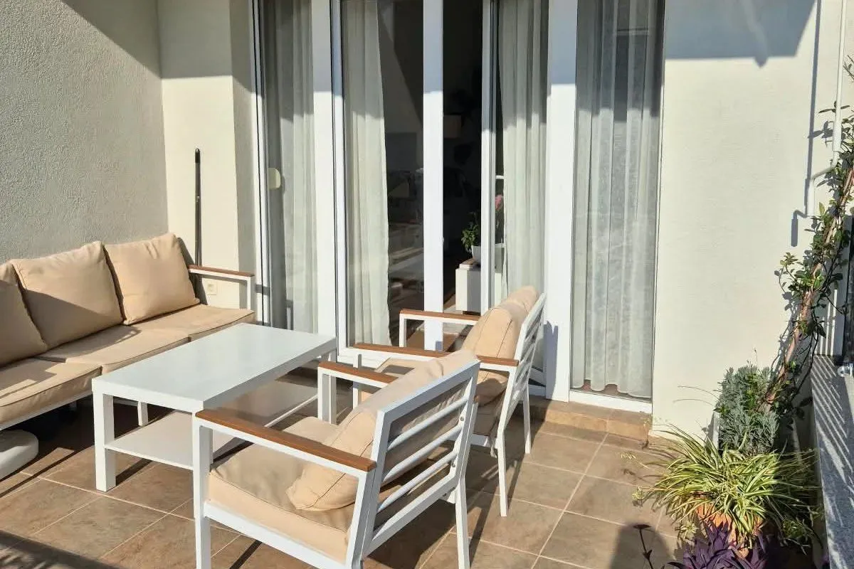Furnished terrace with seating set in front of balcony doors.