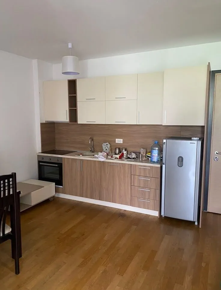 Small kitchen with wooden elements and a refrigerator in the room.