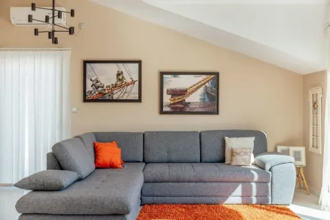 Dnevna soba sa ugaonom garniturom, slikama na zidu i modernim lusterom. - image 3