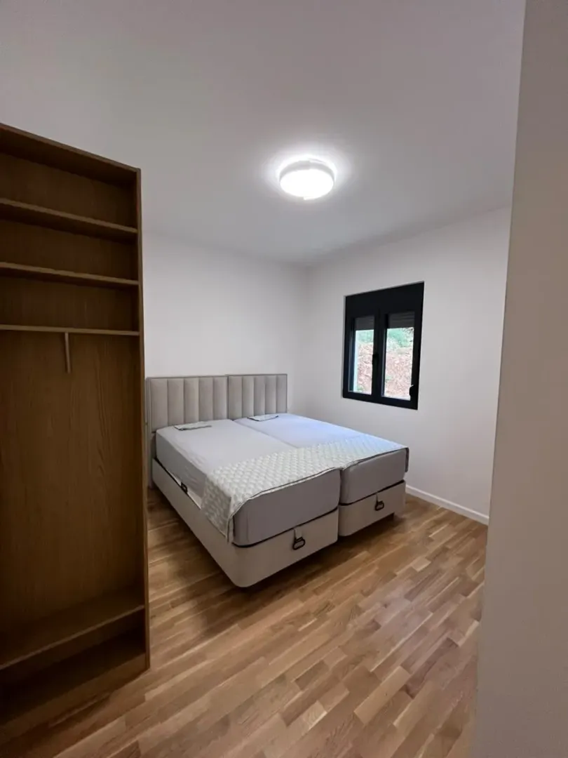Bright bedroom with a double bed and wooden flooring.