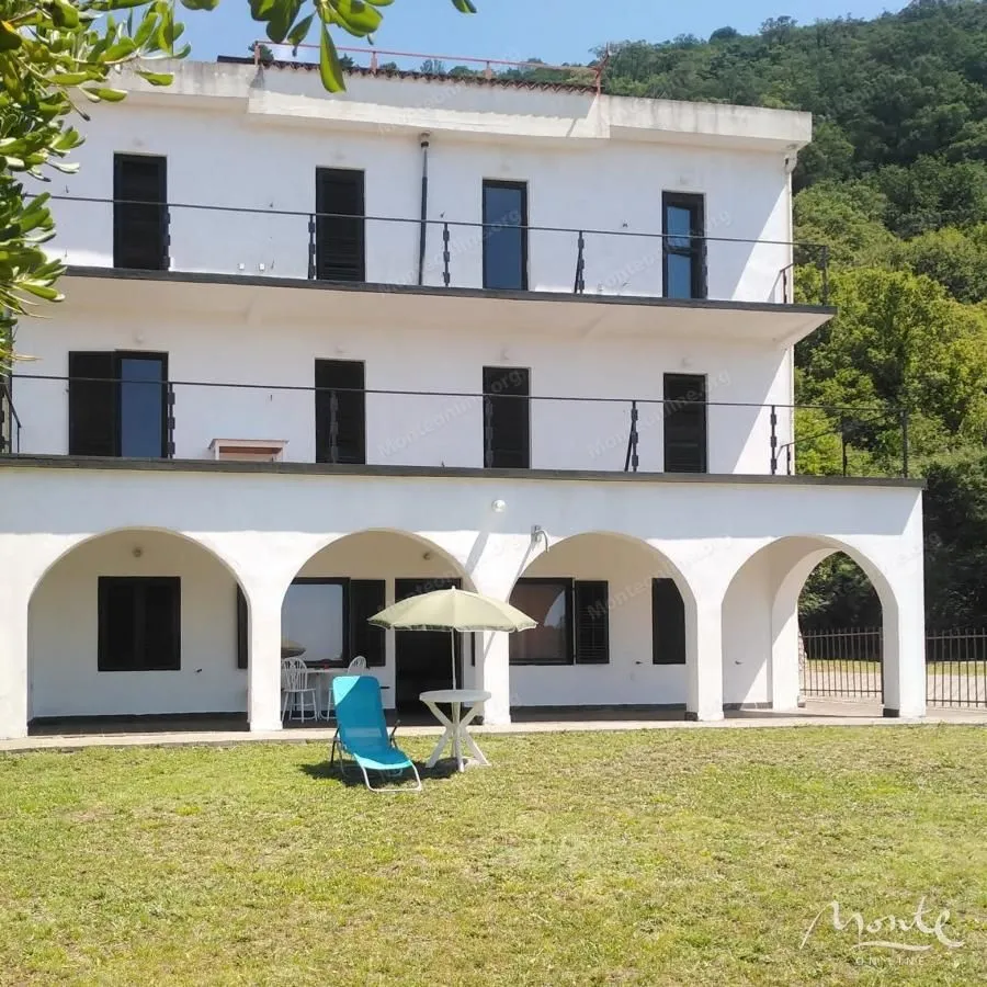View of the facade and yard of a multi-story house with terraces.