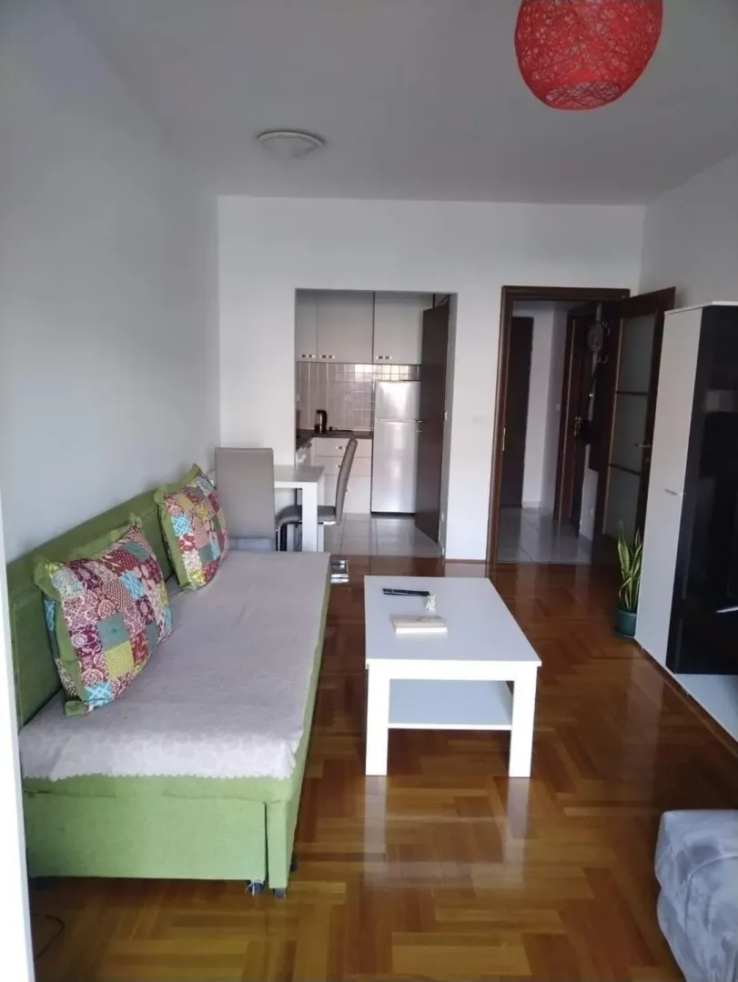 Living room with a sofa, coffee table and view towards the kitchen and hallway.