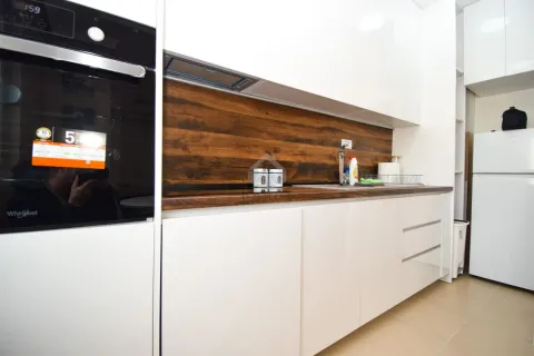 Modern white kitchen with a wooden countertop and built-in oven. - image 4