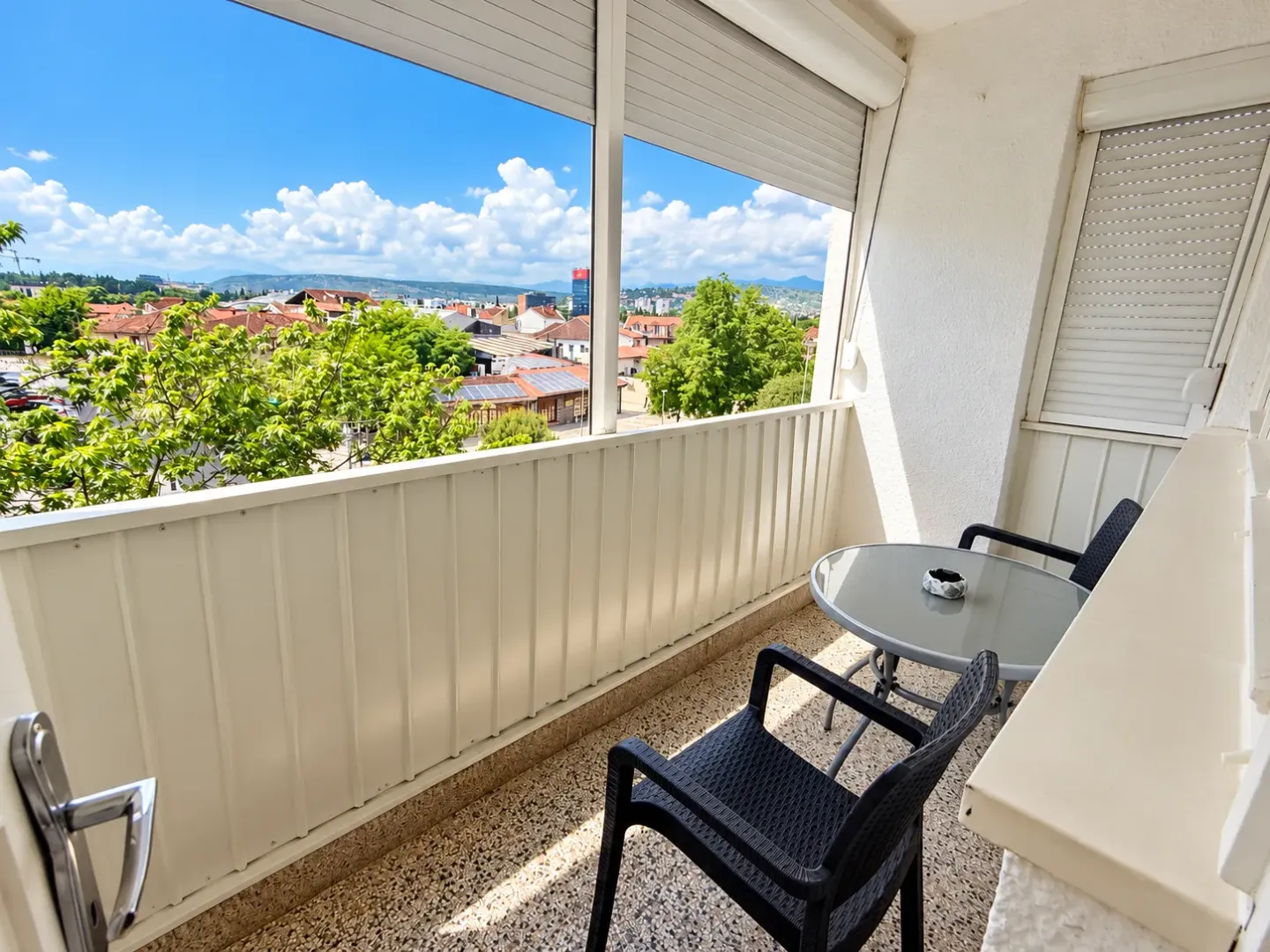 Covered balcony with seating furniture and city view.