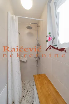 Pogled na tuš kabinu sa staklenom zavesom i drvenom klupom u kupatilu. - image 15