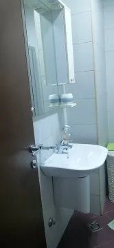 A simple bathroom with a white sink and a mirror. - image 7