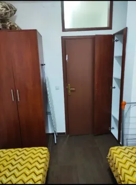 Spavaća soba sa dva kreveta, ormarom i drvenim vratima. - image 4