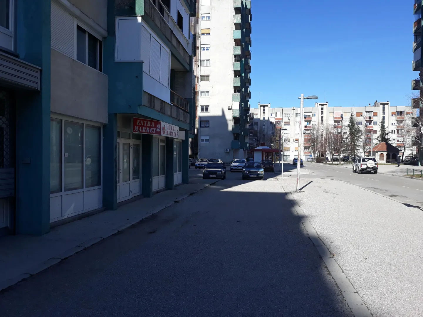 View of the street in front of the residential building with commercial space on the ground floor.