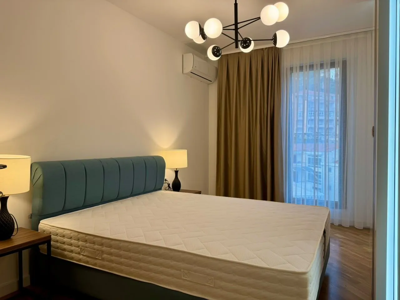 Modern bedroom with a double bed, nightstands, and a chandelier.