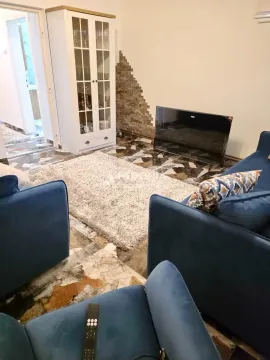 Dnevna soba sa plavim garniturama, belom vitrinom i televizorom na podu. - image 9