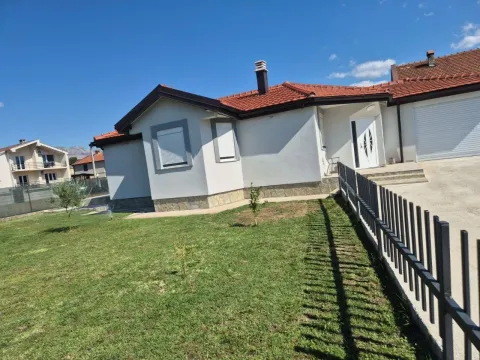 View of the courtyard and front facade of a single-story house with a lawn and fence. - image 12