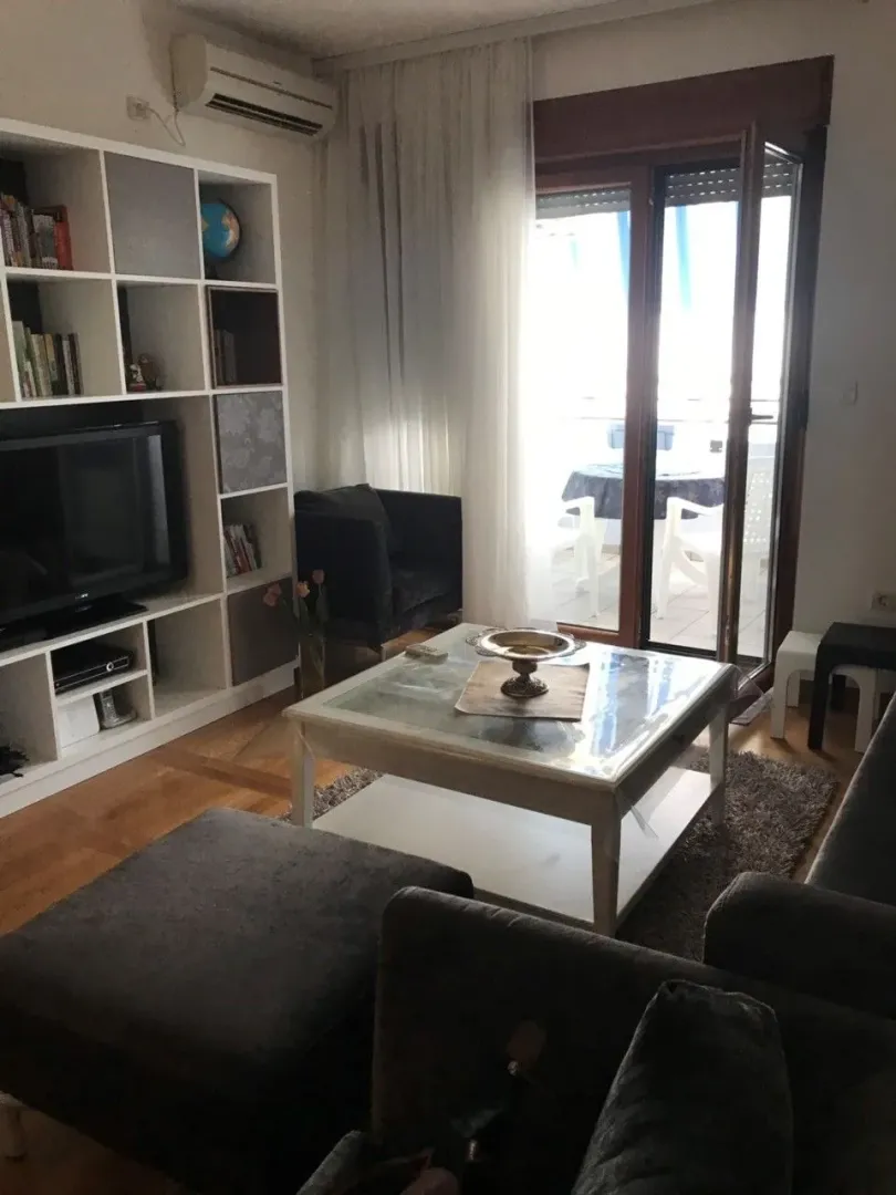 Dnevna soba sa garniturom, klub stolom i izlazom na terasu.
