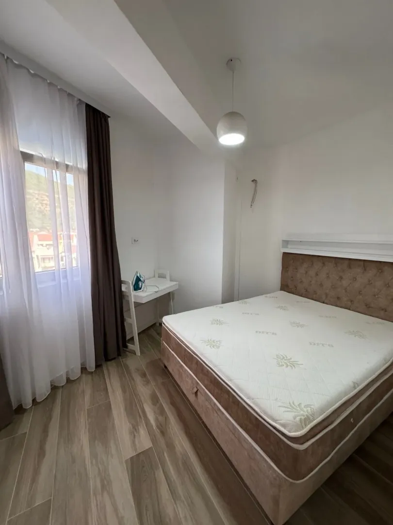 Svjetla spavaća soba sa bračnim krevetom, radnim stolom i prozorom.