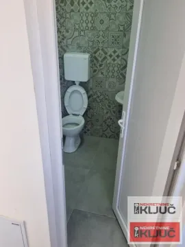 View through an open door into a small bathroom with a toilet and decorative tiles. - image 10