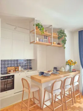 Modern white kitchen with a breakfast bar and dining stools. - image 2