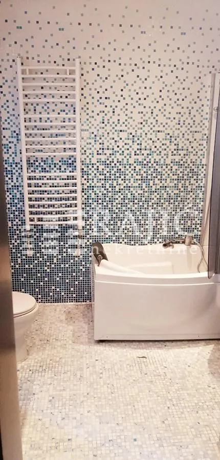 Small bathroom with a bathtub and blue-toned tiles.