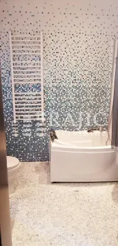 Small bathroom with a bathtub and blue-toned tiles. - image 4