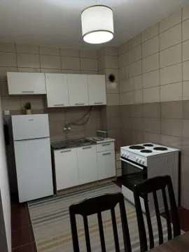 Mala funkcionalna kuhinja sa bijelim elementima i trpezarijskim stolicama. - image 7