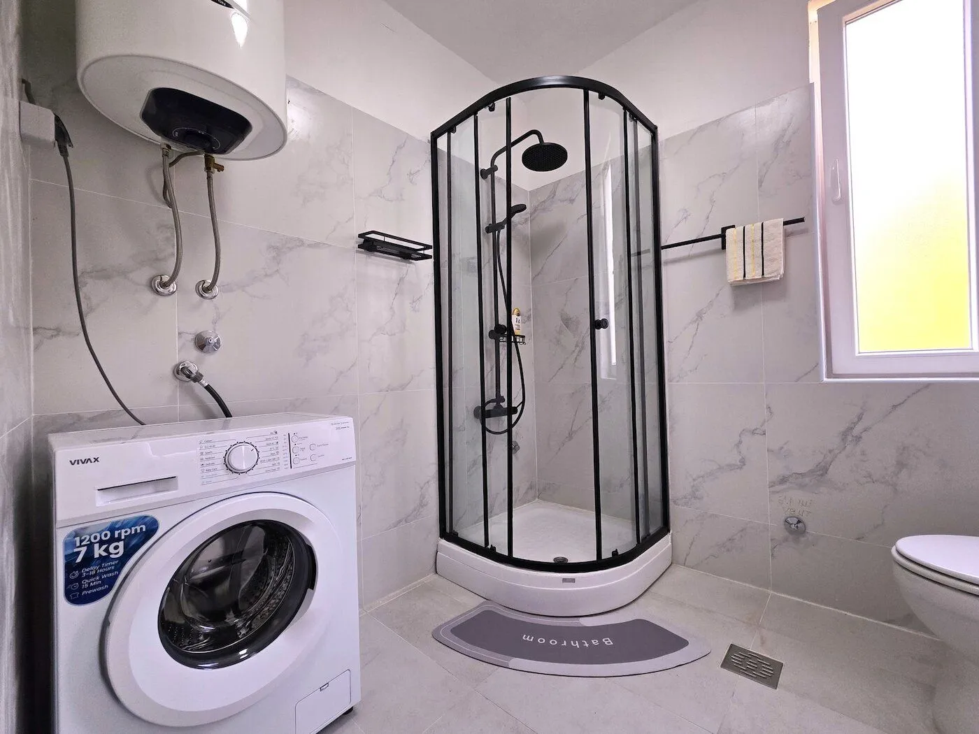 Bathroom equipped with a shower cabin, washing machine, and sanitary facilities.