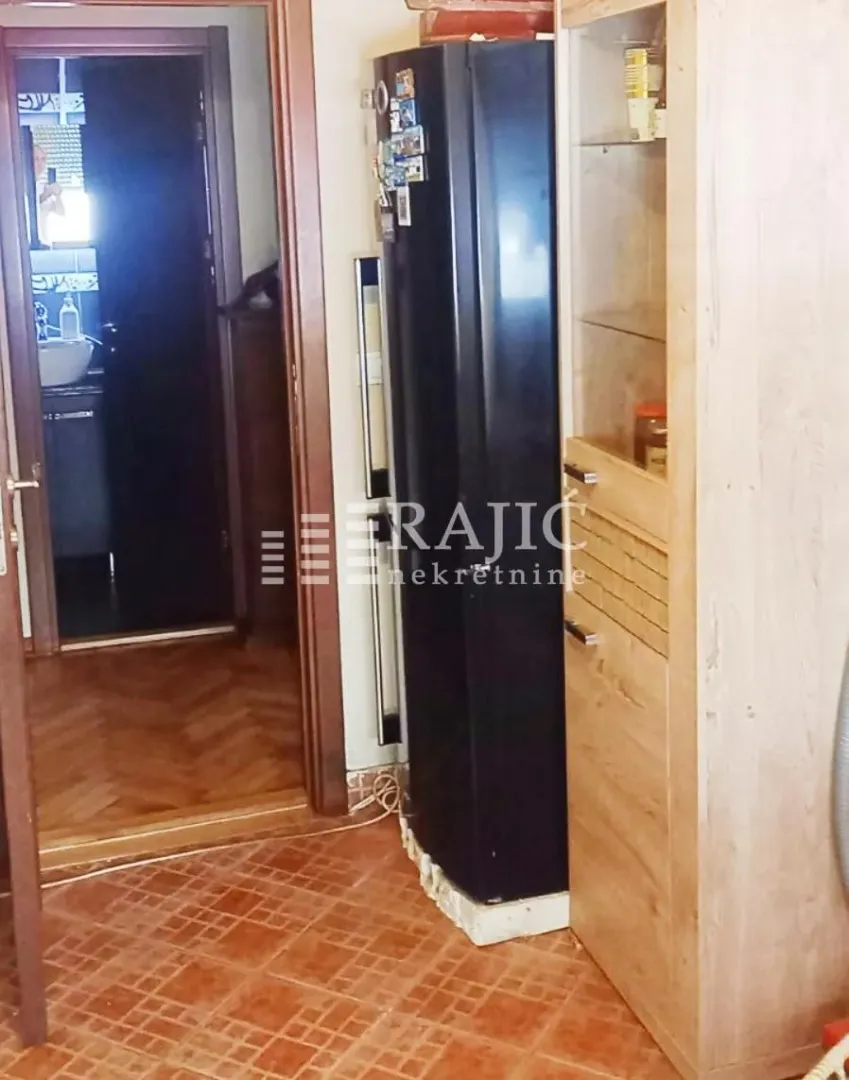 Part of the kitchen with a refrigerator and wooden elements.
