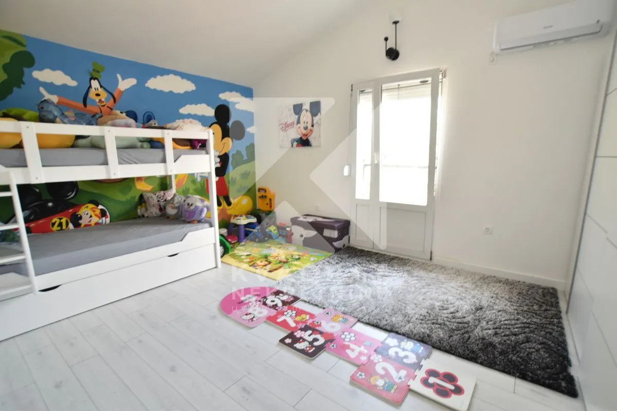 Children's bedroom with a bunk bed and cartoon-themed wallpaper.