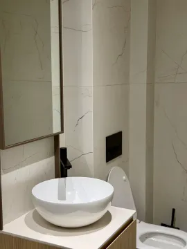 Modern bathroom with a basin, mirror, and toilet tiled with marble-effect tiles. - image 5