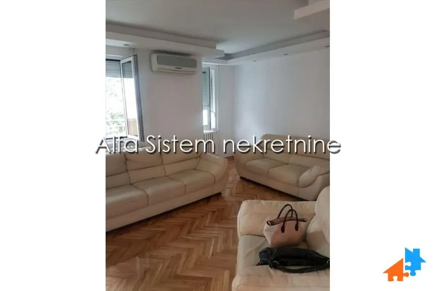 Dnevna soba sa garniturom za sedenje i parketom na podu.