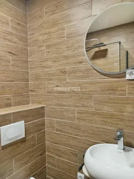Kupatilo obloženo keramičkim pločicama u imitaciji drveta sa umivaonikom i ogledalom. - image 15