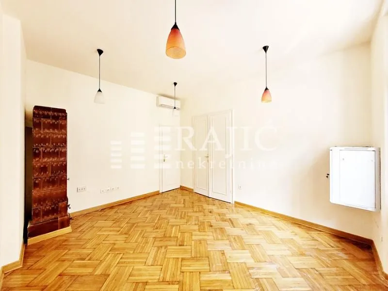 Empty room with wooden parquet flooring, a wood-burning stove, and hanging lamps.