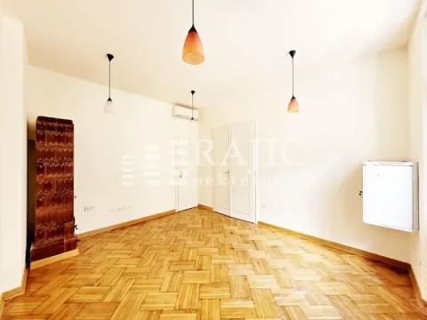 Empty room with wooden parquet flooring, a wood-burning stove, and hanging lamps. - image 3