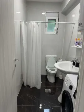 Smaller bathroom equipped with sanitary facilities, a shower curtain, and a washing machine. - image 6