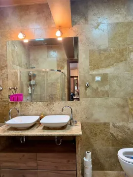 Bathroom with double sinks, large mirror, and beige tiles. - image 16