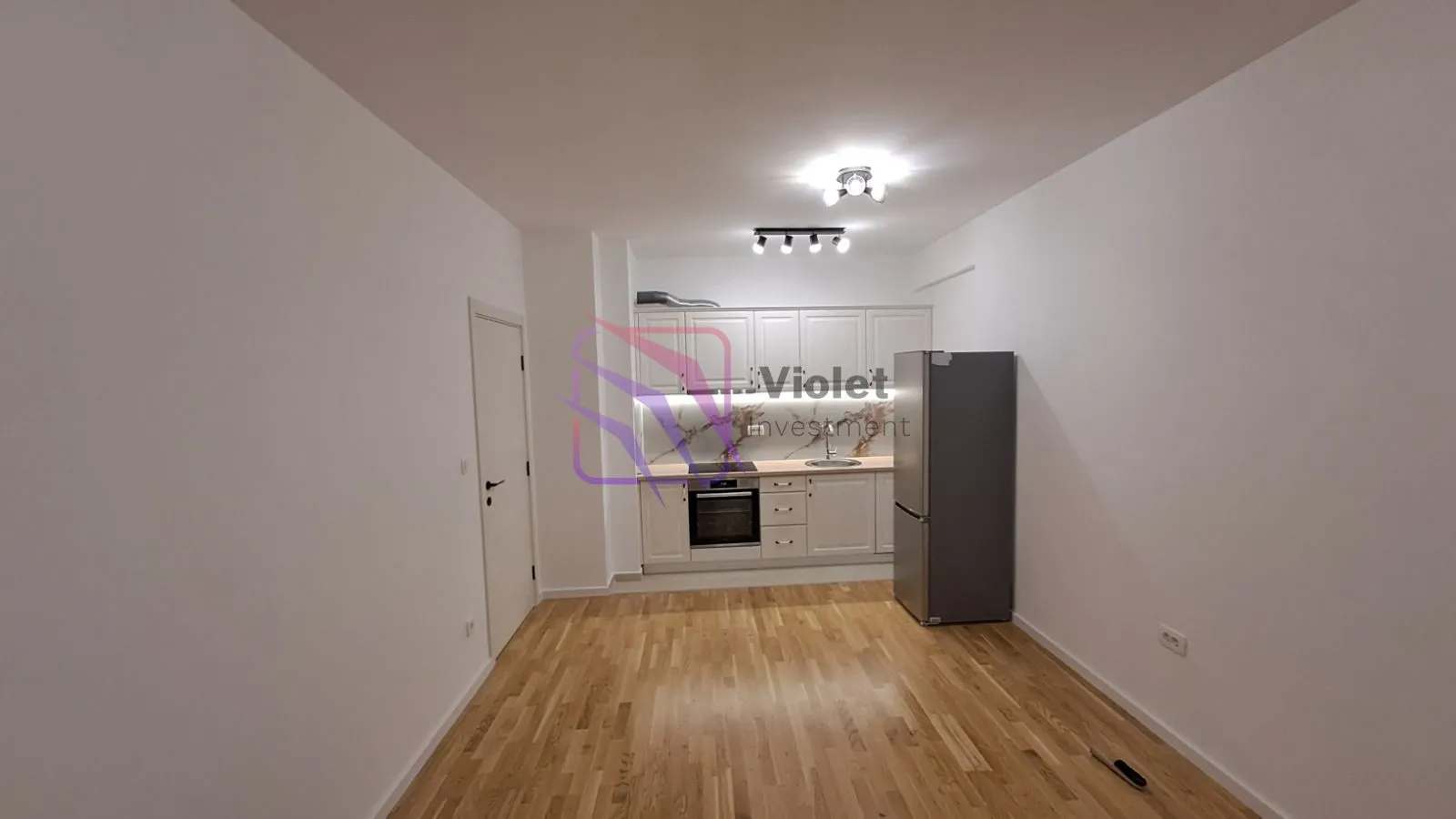 View of the kitchen with white cabinetry and hardwood flooring.