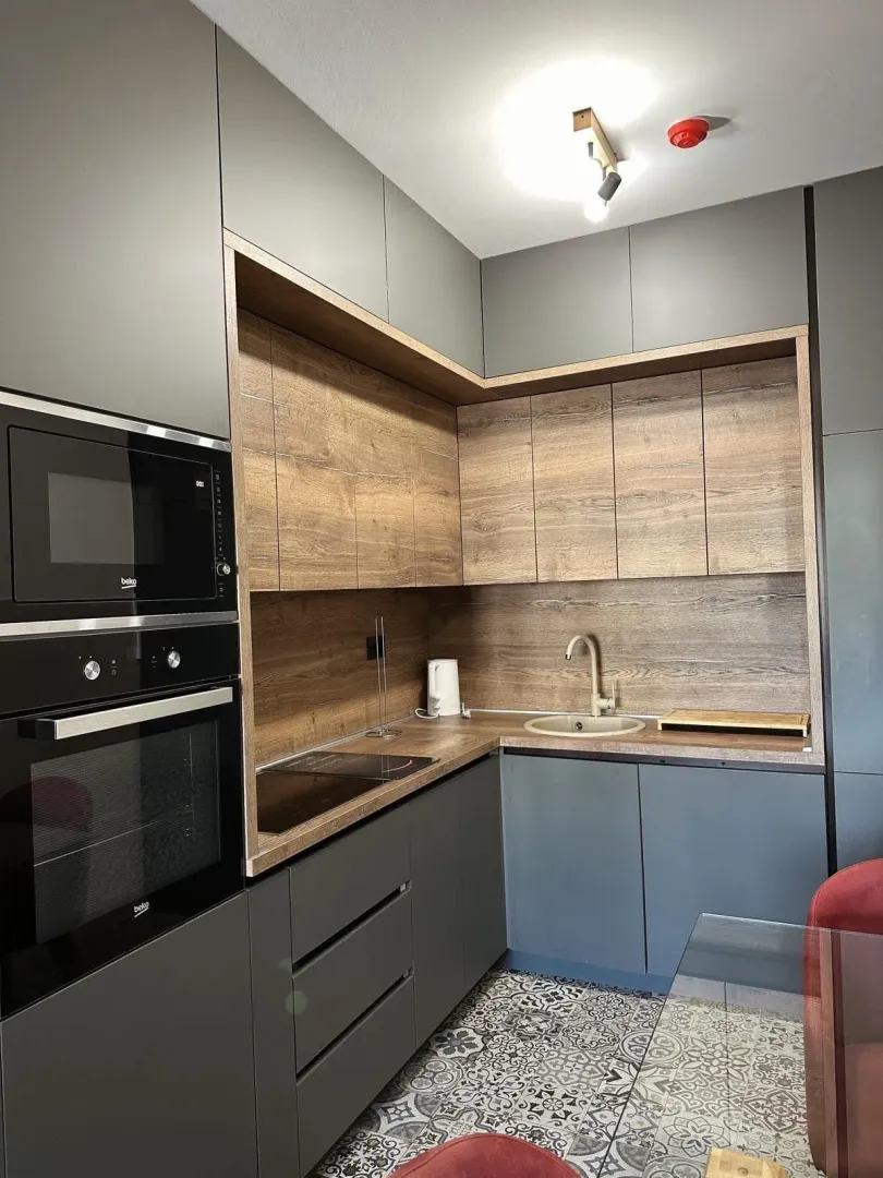 Modern kitchen with grey cabinets and wood-grain details.