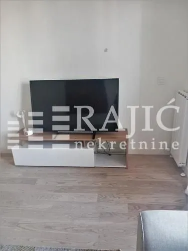 Dnevna soba sa televizorom i komodom.