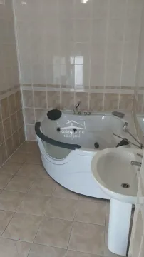 Bathroom equipped with a corner whirlpool bathtub and a washbasin. - image 8